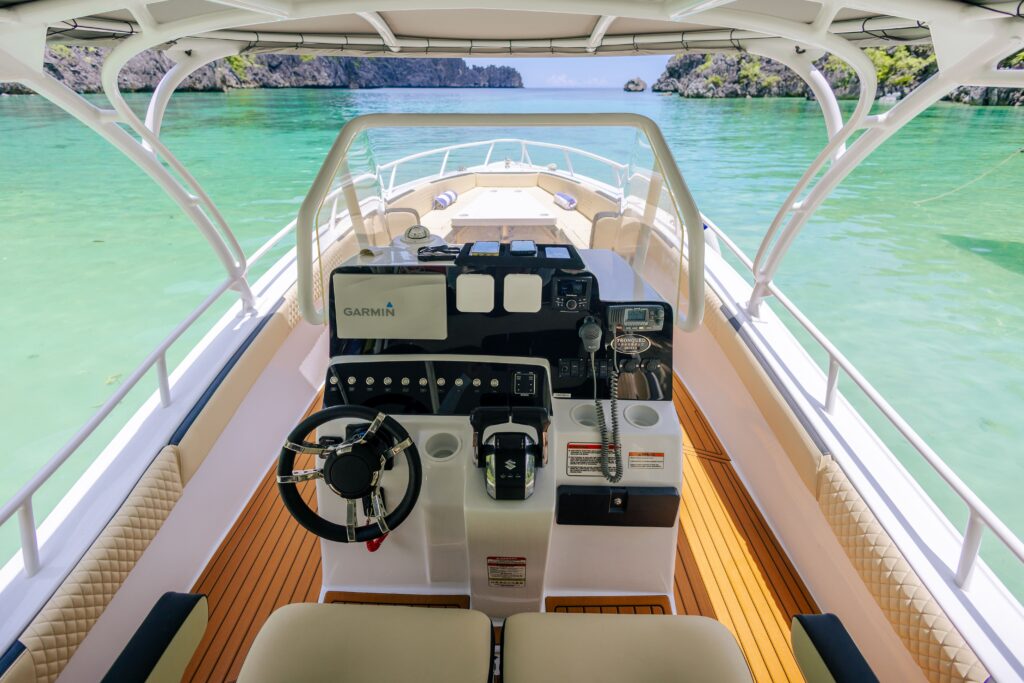View from the helm of a boat on turquoise water with islands in the distance.